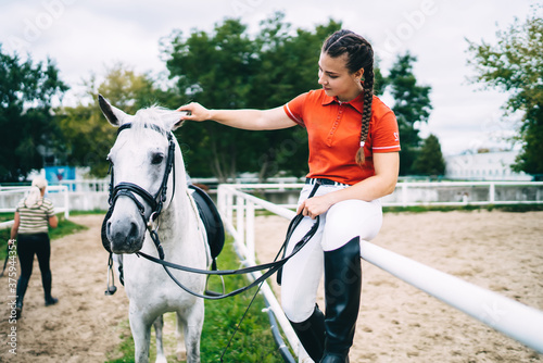 Female jockey resting on barrier near horse