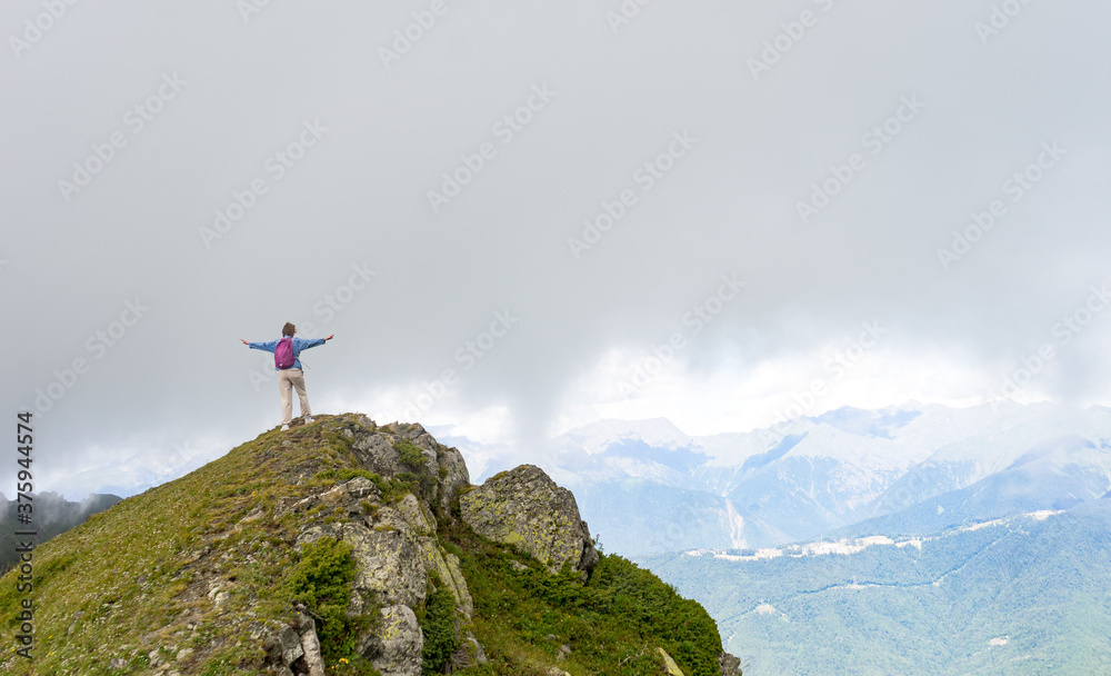 Young hiker stand in beautiful mountains on hiking trip. Active person resting outdoors in  nature. Backpacker camping outside recreation active