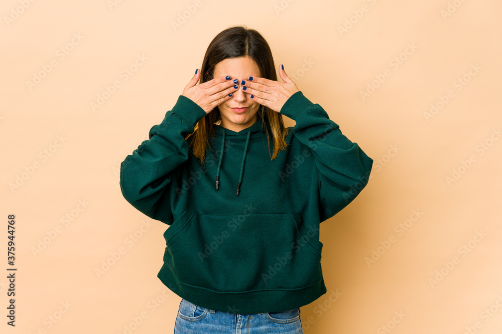 Young woman isolated on beige background afraid covering eyes with hands.