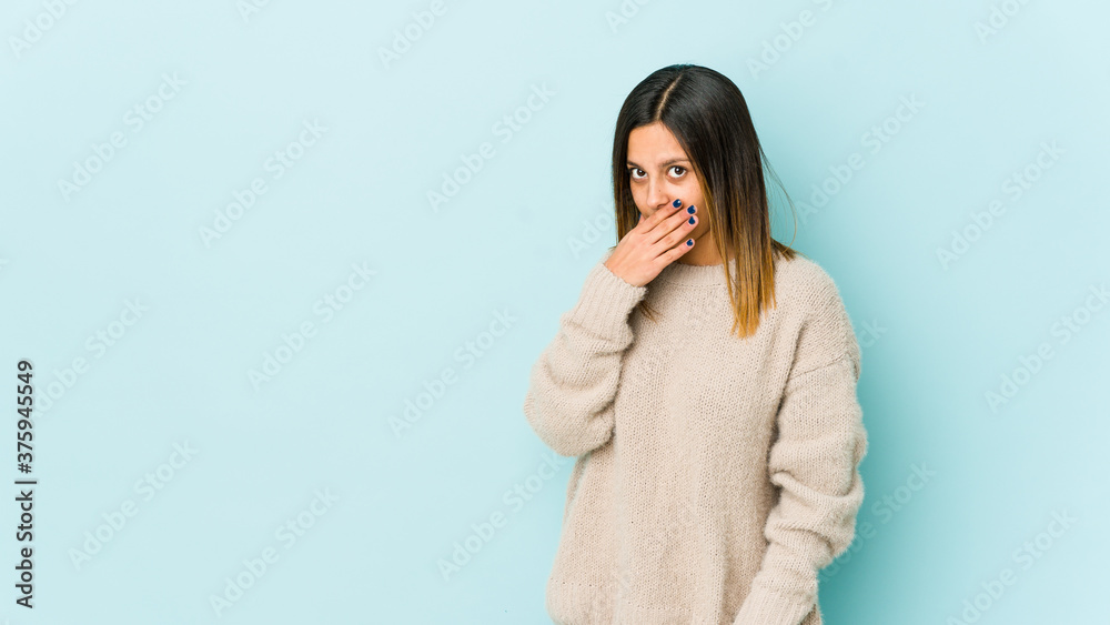 Young woman isolated on blue background covering mouth with hands looking worried. Young woman isolated on blue background covering mouth with hands looking worried.