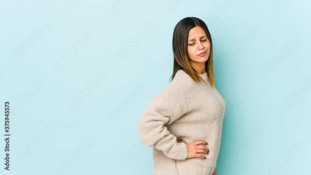 Young woman isolated on blue background suffering a back pain. Young woman isolated on blue background suffering a back pain.