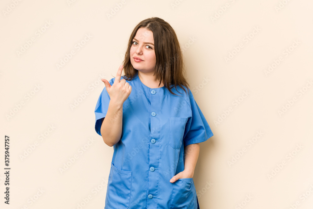 Young curvy nurse woman pointing with finger at you as if inviting come closer. Young curvy nurse woman pointing with finger at you as if inviting come closer.