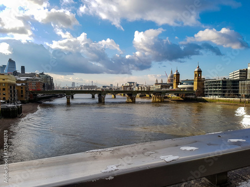 Snow melting on metall at bridge in London city clouds moving away sunshine river thames towers view old historic uk photo