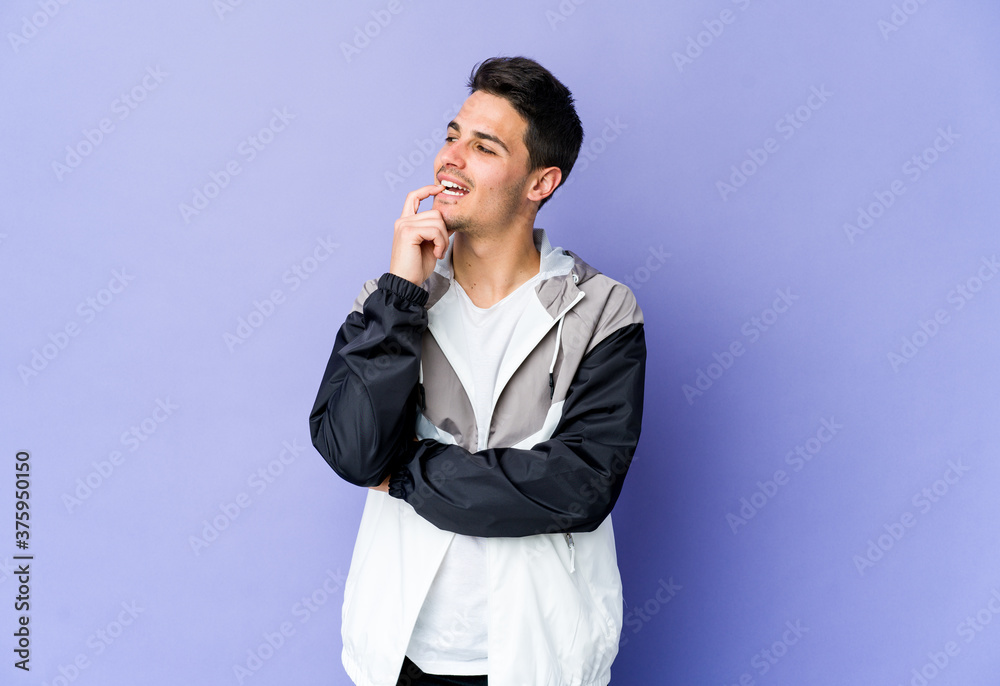 Young caucasian man isolated on purple background relaxed thinking about something looking at a copy space. Young caucasian man isolated on purple background relaxed thinking about something looking at a copy space.