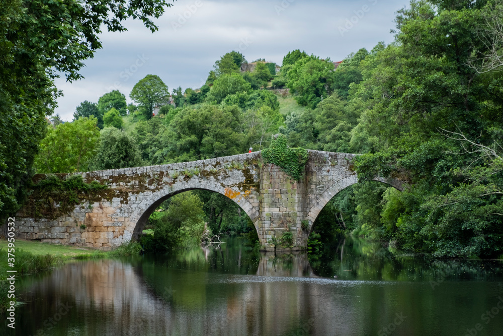 Medieval bridge over Arnoia river in Allariz, Ourense. Galicia. Spain. Cloudy day.