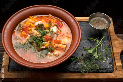 Ukha royally, fish soup, from several varieties of fish, in a clay plate, on a wooden board
