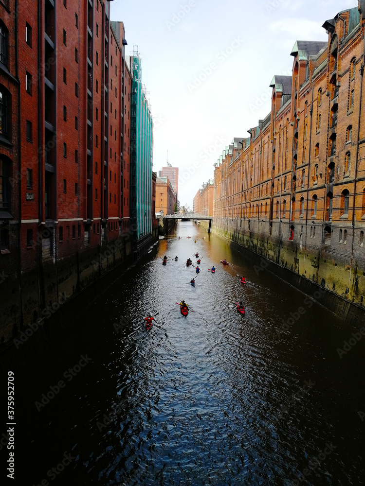 Kayakers canoeing on a canal under bridges at Speicherstadt Hamburg
