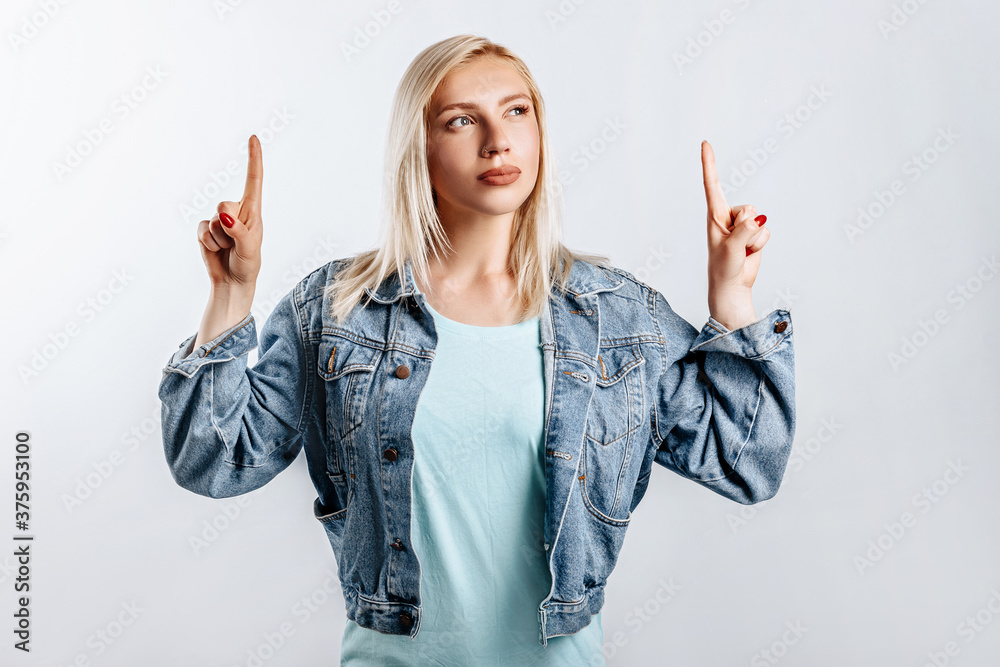 Look here. Young beautiful blonde woman points her fingers to the top thinks and makes a decision. The woman thought about the choice. Place for advertising. Look here. Young beautiful blonde woman points her fingers to the top thinks and makes a decision. The woman thought about the choice. Place for advertising.
