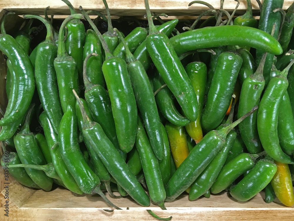 High angle close-up view of a box with fresh green pepperoni displayed for sale at a grocery market High angle close-up view of a box with fresh green pepperoni displayed for sale at a grocery market