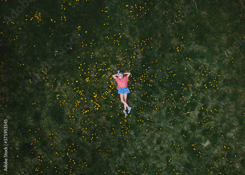 Ariel view of a child laying in the grass with dandelions 