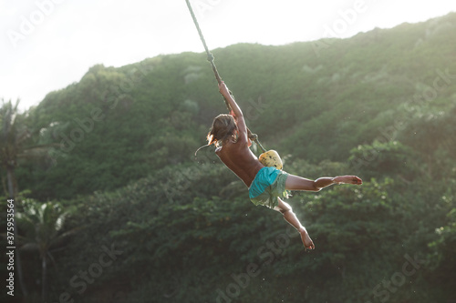 Boy rope swinging in Kauai, Hawaii.  photo