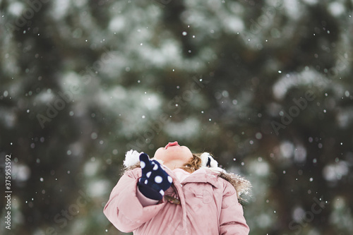 Little girl catching snowflakes with tongue  photo