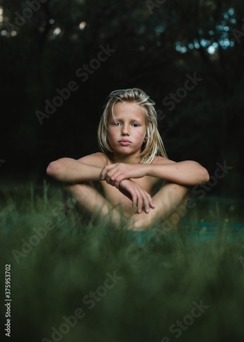 Portrait of a boy sitting in grass in the summer