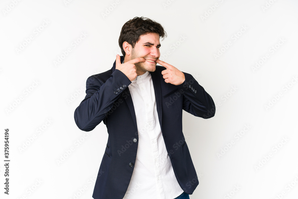 Young business man isolated on white background smiles, pointing fingers at mouth. Young business man isolated on white background smiles, pointing fingers at mouth.