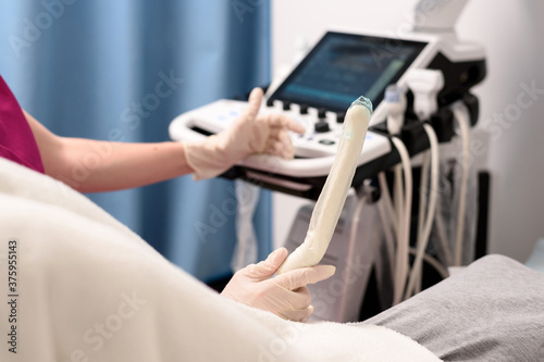 A gynecologist holds in his hand a transvaginal ultrasound scanner with a gel for vaginal examination of a woman. Ultrasound of the pelvic organs. Close-up, selective focus. Medical equipment concept. photo