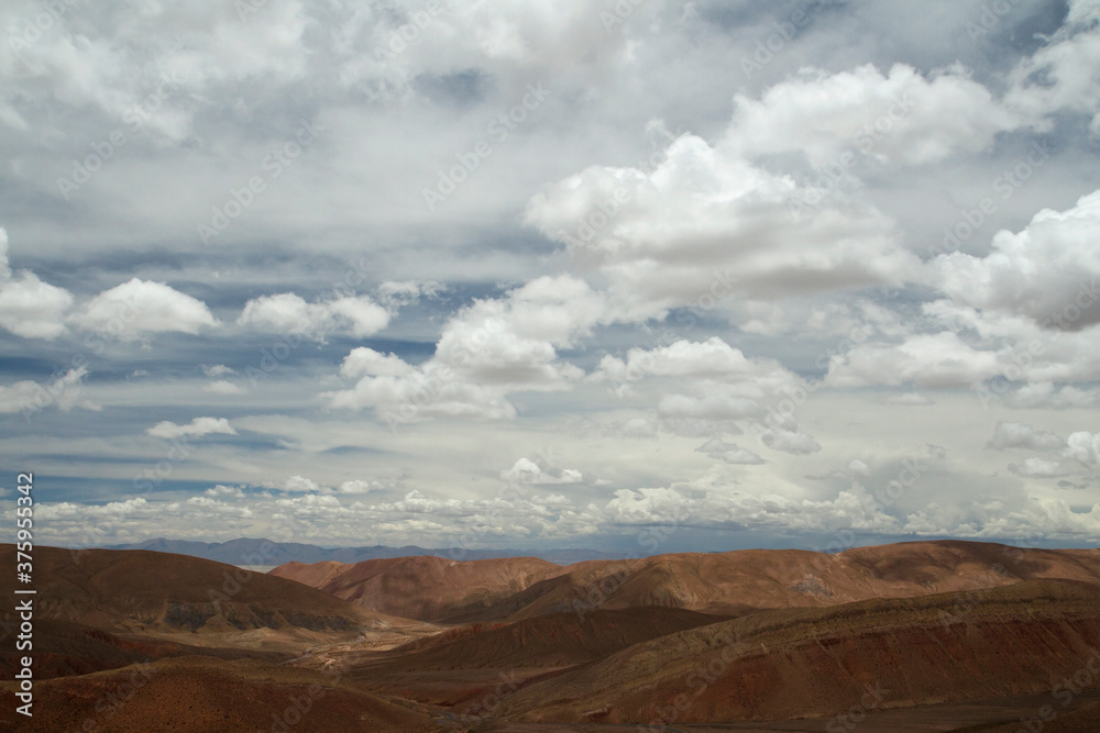 Desert landscape. Aerial view of the brown arid mountains and valley under a beautiful cloudy sky.