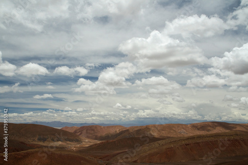Desert landscape. Aerial view of the brown arid mountains and valley under a beautiful cloudy sky. © Gonzalo