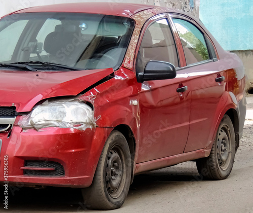 A dented red car. The consequence of a small accident on the road.