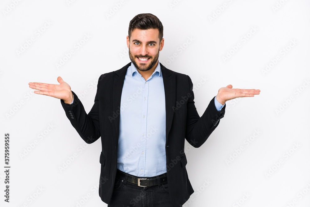 Young caucasian business man against a white background isolated makes scale with arms, feels happy and confident. Young caucasian business man against a white background isolated makes scale with arms, feels happy and confident.