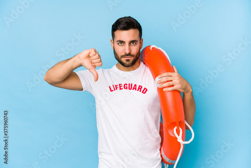 Young handsome lifeguard man isoalted showing a dislike gesture, thumbs down. Disagreement concept. © Asier