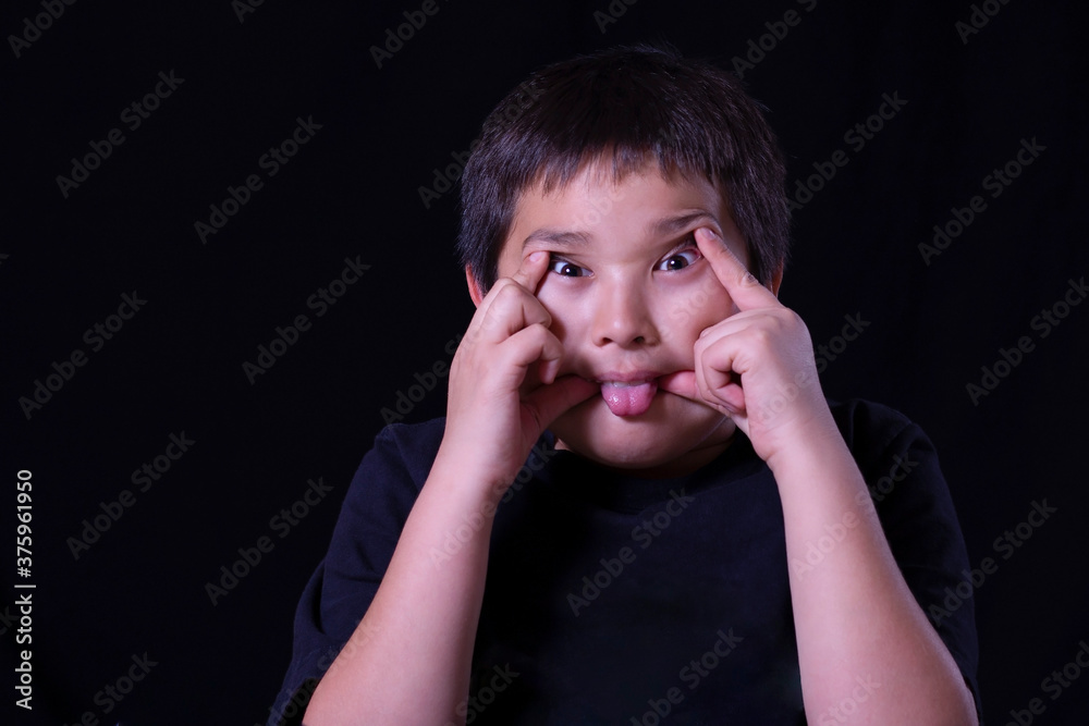 A young boy making a silly face with a black background A young boy making a silly face with a black background