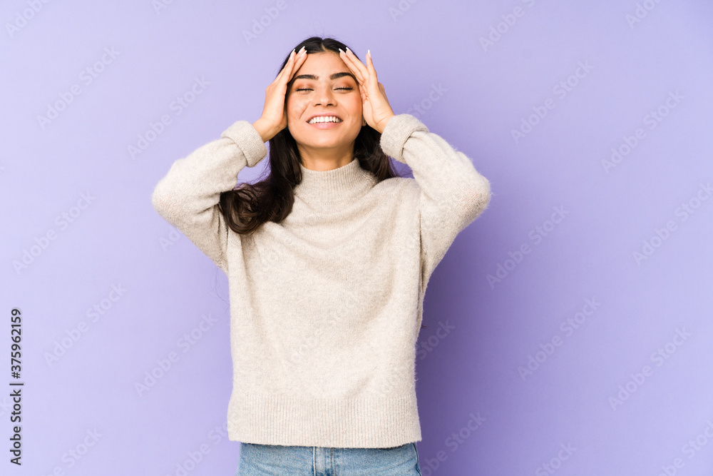 Young indian woman isolated on purple background laughs joyfully keeping hands on head. Happiness concept. Young indian woman isolated on purple background laughs joyfully keeping hands on head. Happiness concept.