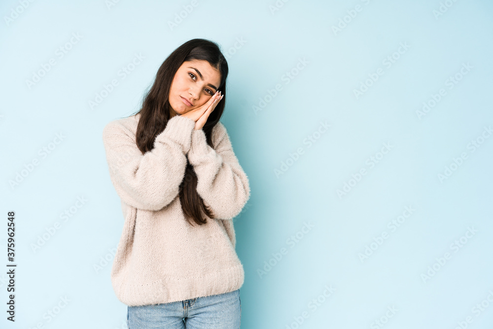 Young indian woman isolated on blue background yawning showing a tired gesture covering mouth with hand. Young indian woman isolated on blue background yawning showing a tired gesture covering mouth with hand.