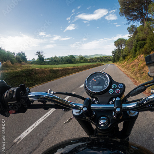 Riding an old black motorbike with speedometer on a tarmac road from a driver point of view