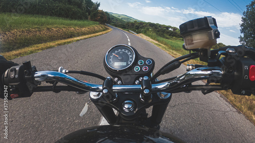 Riding an old black motorbike with speedometer on a tarmac road from a driver point of view