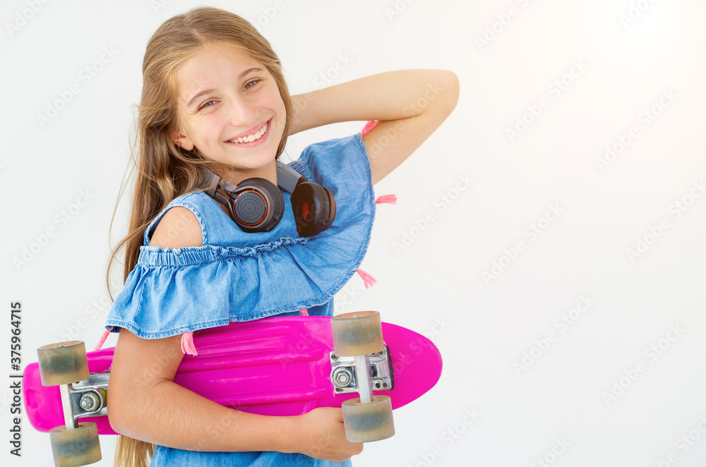 Laughing female kid with penny board and headphones Laughing female kid with penny board and headphones