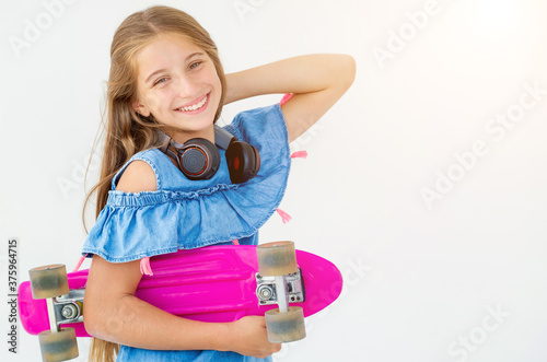 Laughing female kid with penny board and headphones