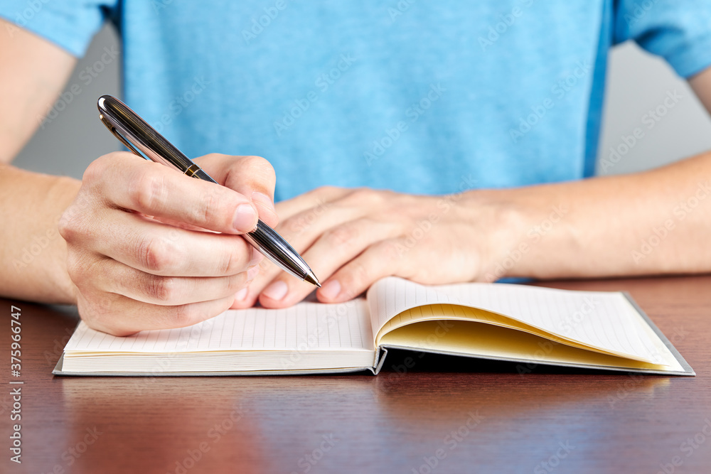 caucasian male person writing to diary or notepad. close up. office paperwork concept. planning concept.person dressed casual clothes caucasian male person writing to diary or notepad. close up. office paperwork concept. planning concept.person dressed casual clothes