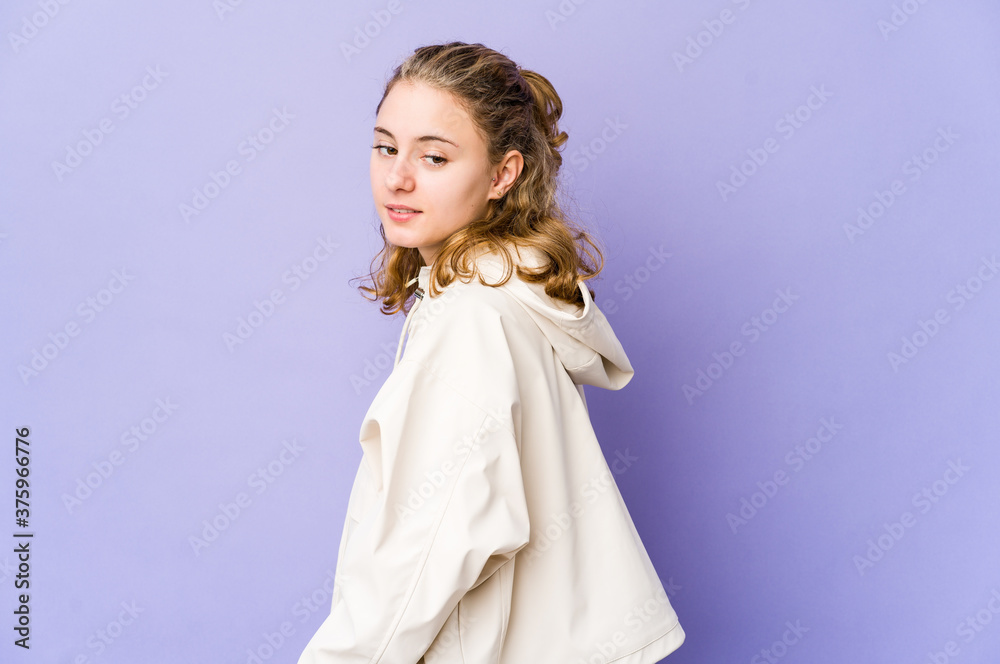 Young caucasian woman on purple background looks aside smiling, cheerful and pleasant.