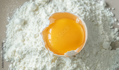 Broken raw chicken egg with flour, top view