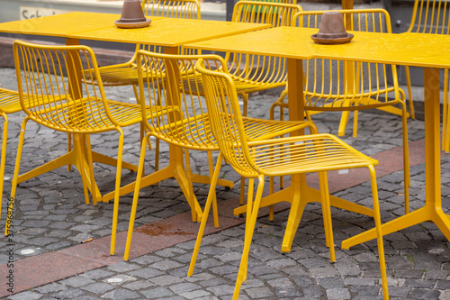 yellow tables and chairs of a street cafe after the rain