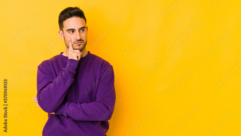 Young caucasian man isolated on yellow bakground contemplating, planning a strategy, thinking about the way of a business.