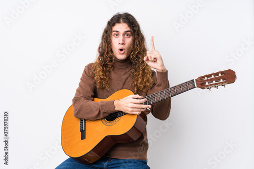 Young caucasian man playing guitar isolated having some great idea, concept of creativity.