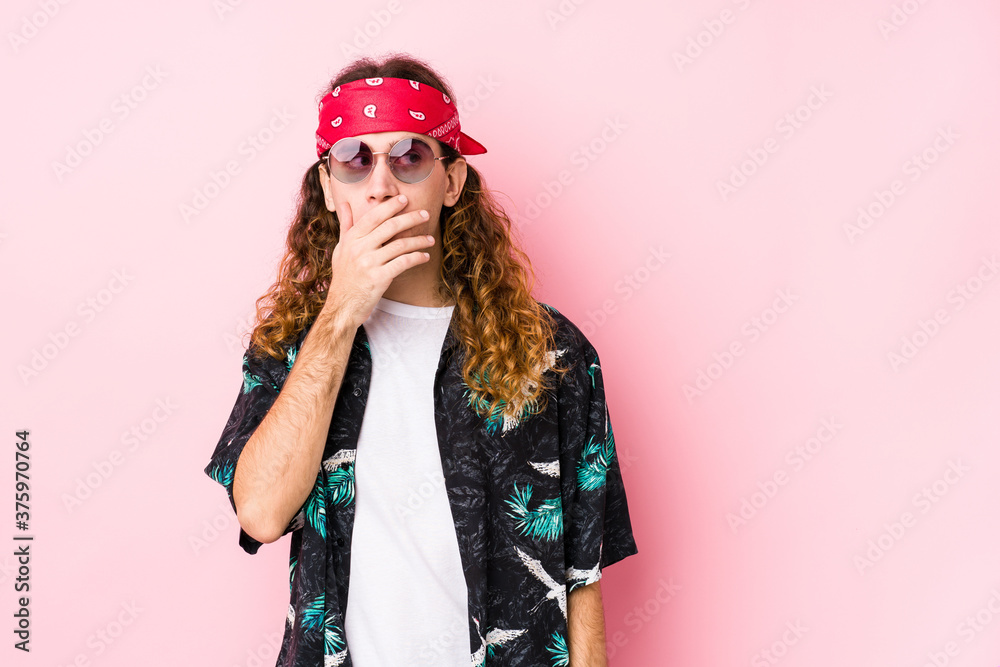 Young hippie caucasian man isolated thoughtful looking to a copy space covering mouth with hand.