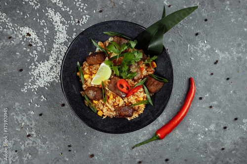 Fried rice with beef and vegetables on a gray textured background