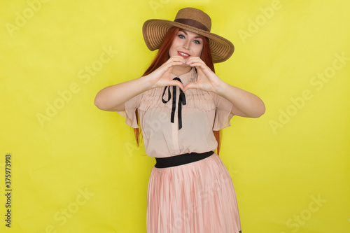 Red haired woman in straw hat over yellow background