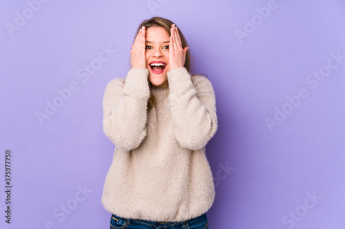 Young caucasian woman isolated on purple background having fun covering half of face with palm.