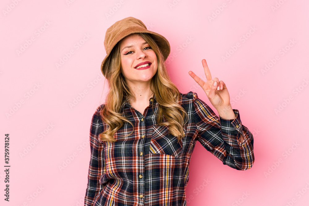Young caucasian woman wearing a hat isolated joyful and carefree showing a peace symbol with fingers. Young caucasian woman wearing a hat isolated joyful and carefree showing a peace symbol with fingers.
