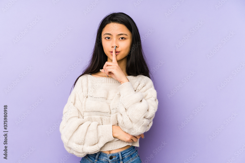 Young chinese woman isolated on a purple background keeping a secret or asking for silence. Young chinese woman isolated on a purple background keeping a secret or asking for silence.