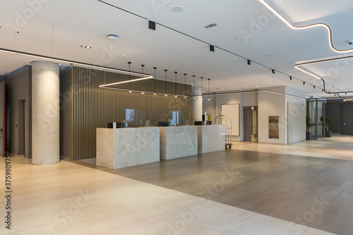 Interior of a hotel lobby with reception desks with transparent covid plexiglass lexan clear sneeze guards photo