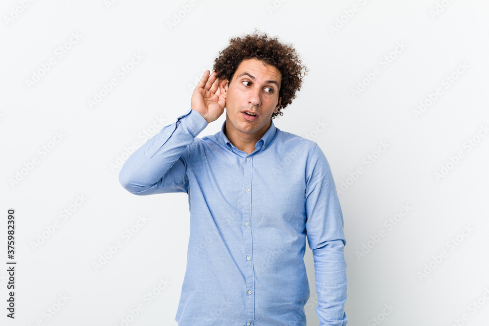 Young curly mature man wearing an elegant shirt trying to listening a gossip. Young curly mature man wearing an elegant shirt trying to listening a gossip.