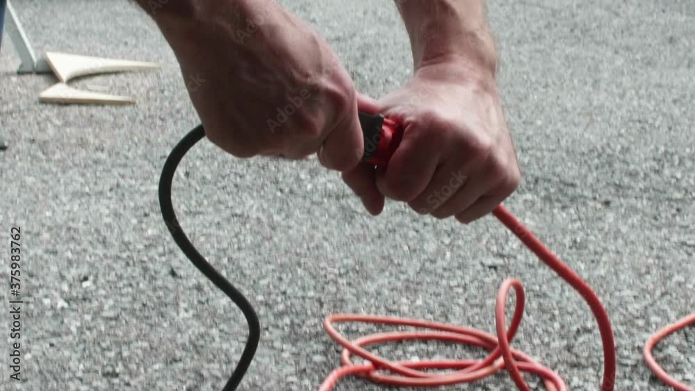 Man unplugging power tool from extension cord outside, Close Up, Slow Motion