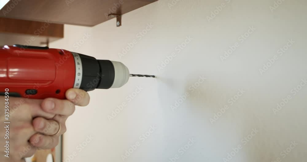 Drilling into Concrete Wall and Opening a Hole with Cordless Red Power Drill in slow mo