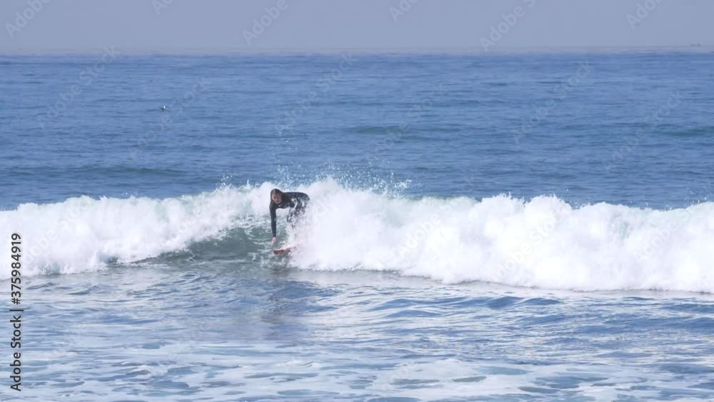 SLOW MOTION (180FPS): A young and experienced woman surfer rides a wave in a wet suit on a sunny day in Southern California SLOW MOTION (180FPS): A young and experienced woman surfer rides a wave in a wet suit on a sunny day in Southern California
