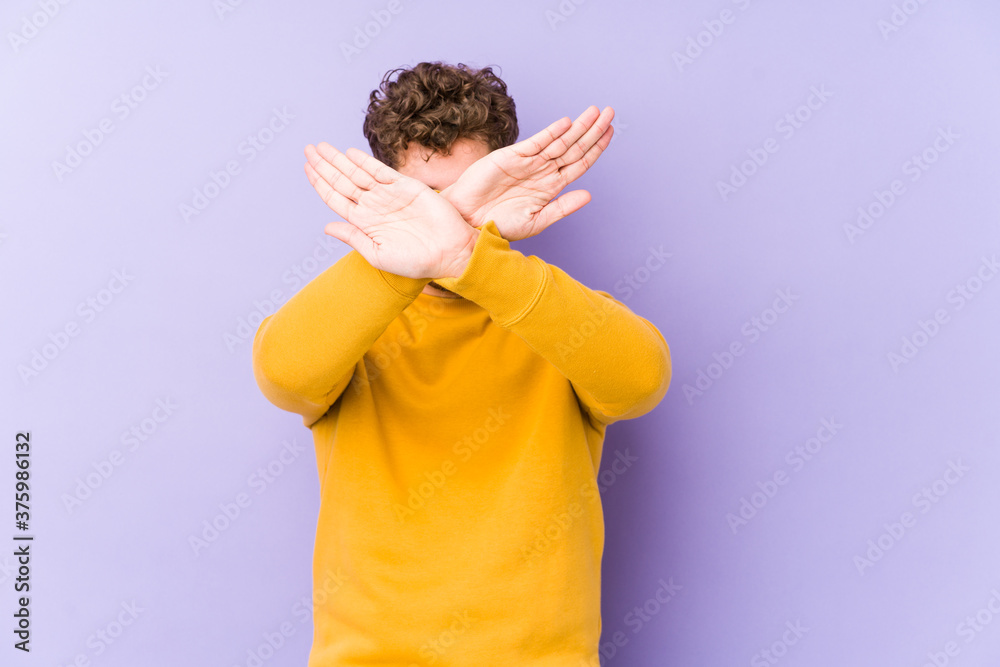 Young blond curly hair caucasian man isolated keeping two arms crossed, denial concept.