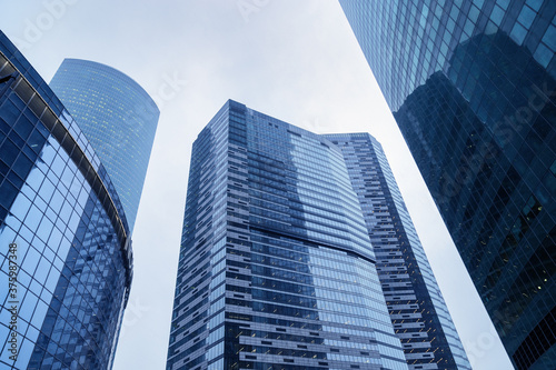 Impressive skyscrapers up to sky. Blue glass building from glass, modern architectural style. Apartments and offices in huge houses.